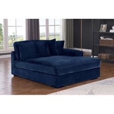 a large blue couch sitting on top of a hard wood floor next to a window