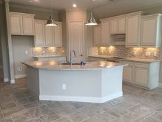 an empty kitchen with white cabinets and marble counter tops in a new construction home that is being built