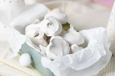 a bowl filled with marshmallows sitting on top of a white table cloth