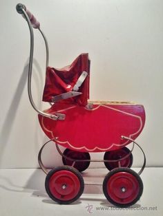 a red toy stroller with a baby in it's seat and handlebars