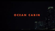 the words ocean cabin are lit up at night in front of tall buildings and skyscrapers