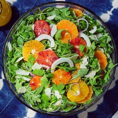 a salad with oranges, onions and spinach in a bowl next to silverware