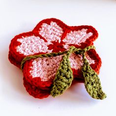 three crocheted red and white flowers sitting on top of a table next to each other