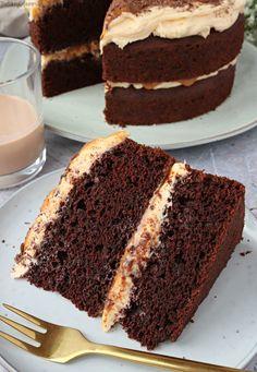 two slices of chocolate cake with white frosting on plates next to a glass of milk