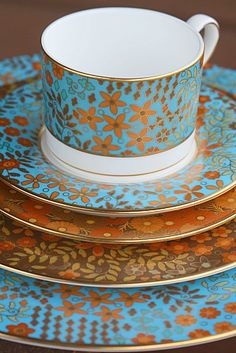 a stack of blue and gold plates on top of each other with flowers painted on them