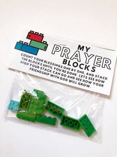 some green legos are in a plastic bag on a white surface with a sticker that says, my prayer blocks