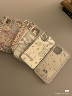 four cell phone cases sitting next to each other on top of a table in front of a book