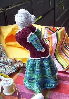 there is a doll that is sitting on the table next to some yarn and scissors