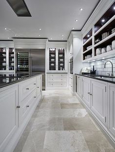 a large kitchen with white cabinets and black counter tops, along with marble flooring