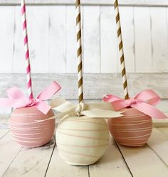 two candy apples with pink bows on them sitting next to each other in front of some candles