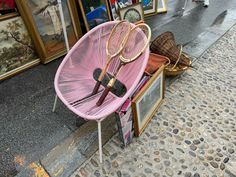 a pink chair with tennis rackets on it sitting in front of a storefront