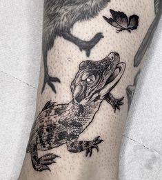 a lizard and bird tattoo on the left leg, with birds flying in the background