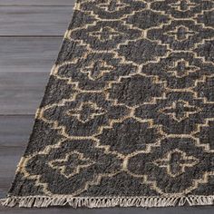 a black and beige rug on a wooden floor