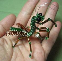 a hand holding a small green beaded lizard ornament