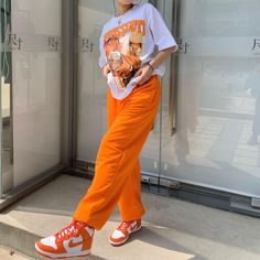 Orange Pants Outfit, Colorful Streetwear, Orange Streetwear, Mode Zara, Orange Pants, Orange Outfit, Tomboy Style Outfits, Streetwear Fashion Women, Woman Standing