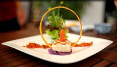 a white plate topped with food on top of a wooden table next to green plants