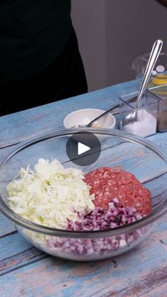 a bowl filled with meat and vegetables on top of a blue wooden table next to two bowls