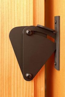 a close up of a door handle on a wooden door with a black triangle shaped hook