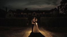 a bride and groom standing in the middle of a road at night with their arms around each other