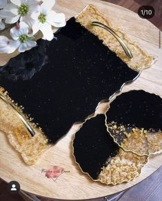 there are two pieces of black and gold paper on top of a table with flowers