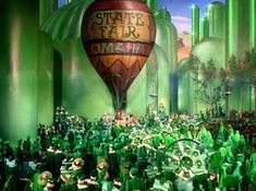 a group of people dressed in green standing next to each other near a hot air balloon with the words state fair on it