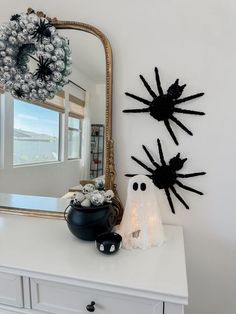 a white dresser topped with a mirror next to a black and white halloween decoration on top of it