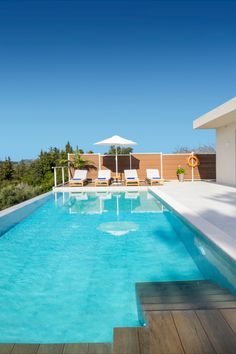 an empty swimming pool with lounge chairs and umbrellas on the roof terrace overlooking the ocean