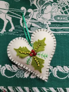 an ornament shaped like a heart with holly leaves