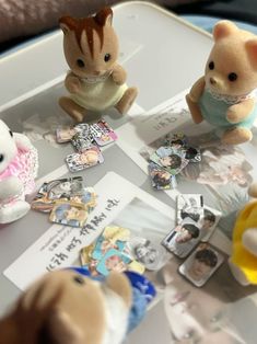 two stuffed animals sitting on top of a table next to some pictures and magnets