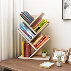 a bookshelf with several books on it next to a potted plant and framed pictures