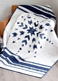 a white and blue quilt sitting on top of a chair next to a stuffed animal