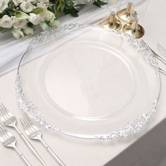 a white table setting with silverware and flowers