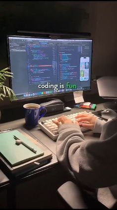 a person sitting at a desk in front of a computer monitor with codeing on it