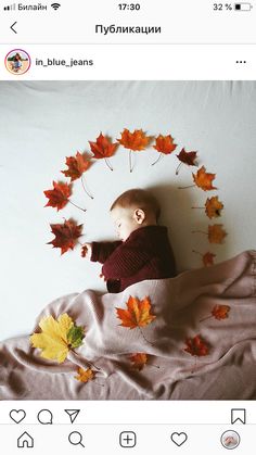 a baby laying on top of a bed covered in leaves