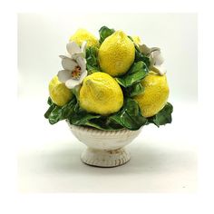 a white bowl filled with lemons and flowers