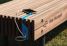 a wooden bench with an electronic device attached to it's back and the words stay charged