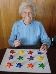 an older woman sitting at a table with a large piece of paper that has stars on it