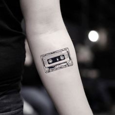 a woman's arm with a tattoo that has an old school cassette on it