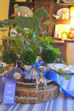 the table is set with blue and white plates, silverware, and green plants