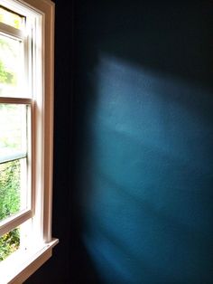 the corner of a room with a window and blue wall painted in teal green