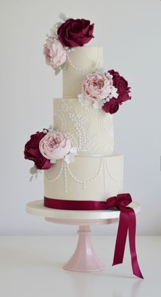 a three tiered wedding cake with flowers on top