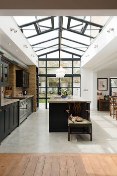 an open kitchen and dining area with wooden floors, black cabinets, and a skylight