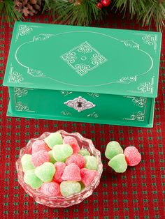 a green box filled with candy next to a bowl of marshmallows on a table