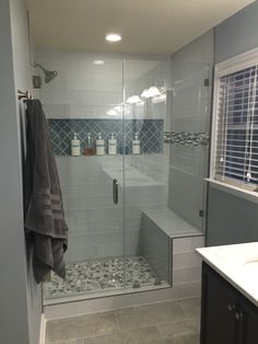 a walk in shower sitting next to a white sink and counter top under a window