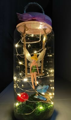 a glass jar filled with fairy lights and a fairy figurine sitting on top of it