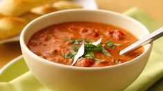 a white bowl filled with soup on top of a green plate next to some bread