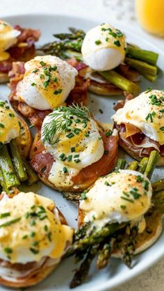 a white plate topped with eggs, asparagus and other food on top of it