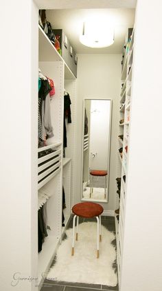 a walk in closet with white shelving and shelves