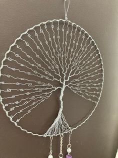 a wire sculpture with beads hanging from it's sides and a tree in the middle