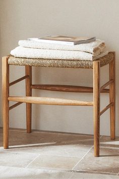 a wooden bench sitting on top of a tile floor next to a white wall with a book on it